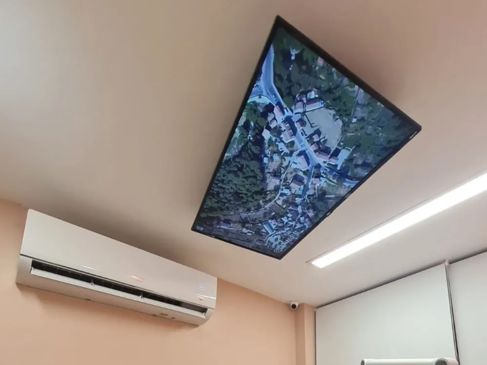 TV instalada no teto da sala de atendimento, acima da cadeira do paciente